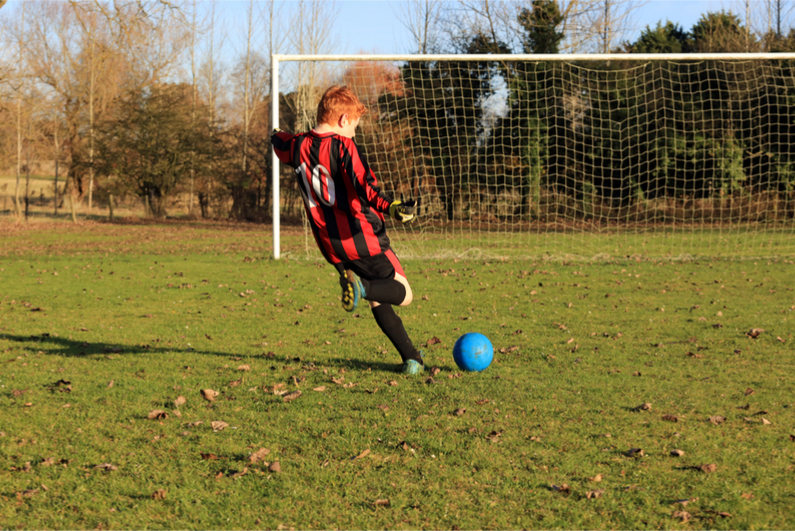 football boy practising kick goal