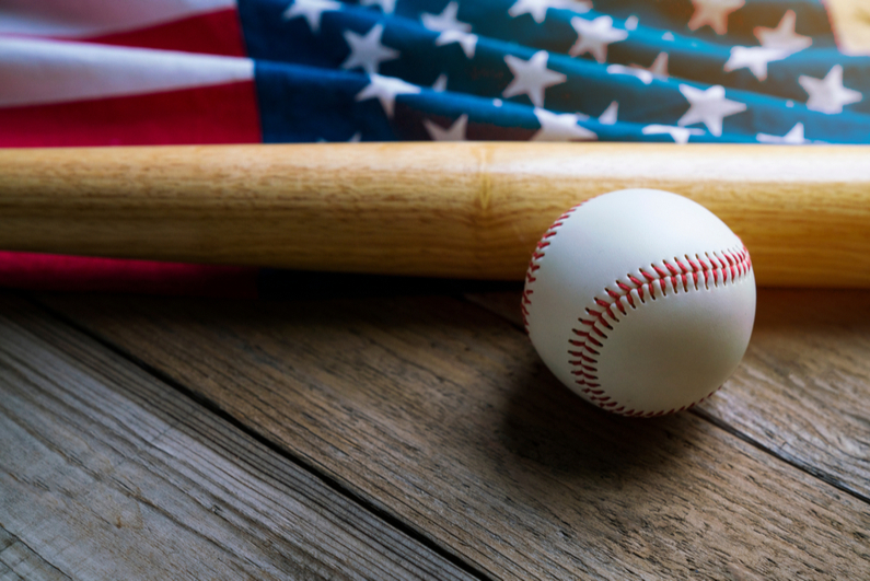 Baseball and bat with US flag in background