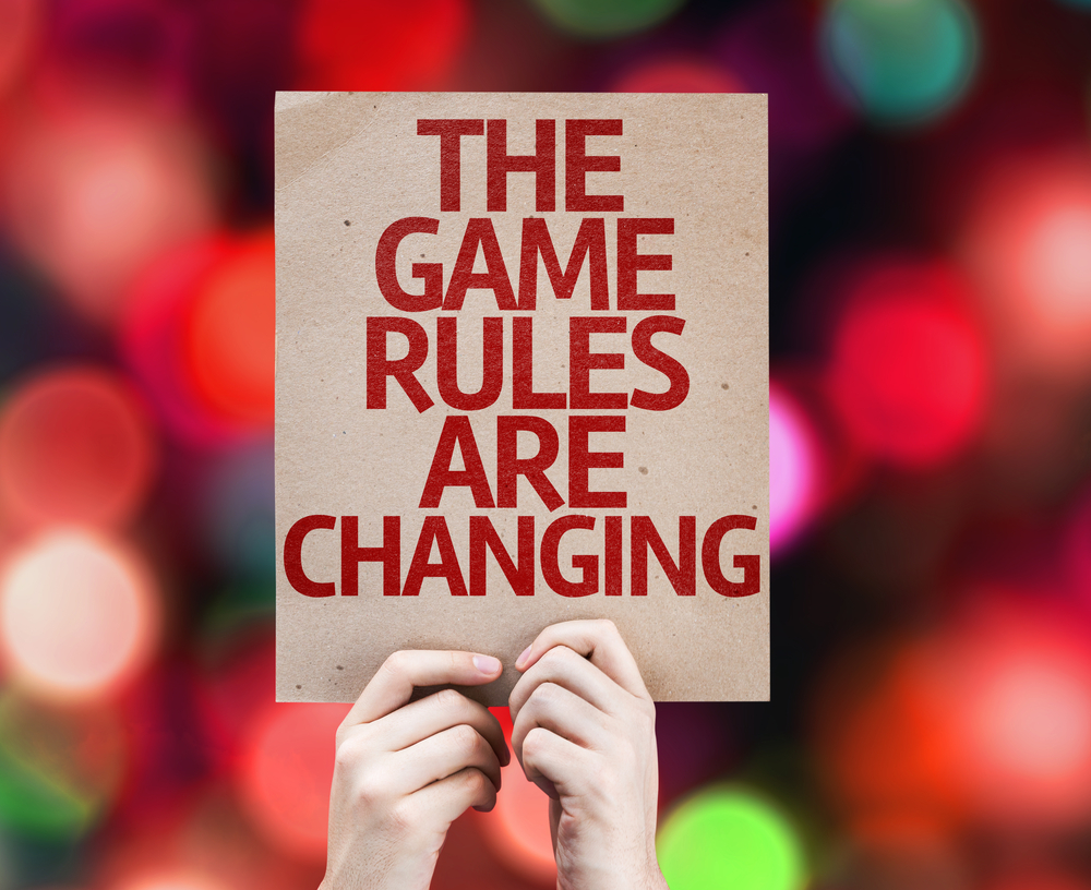 hands holding up a poster that reads the game rules are changing