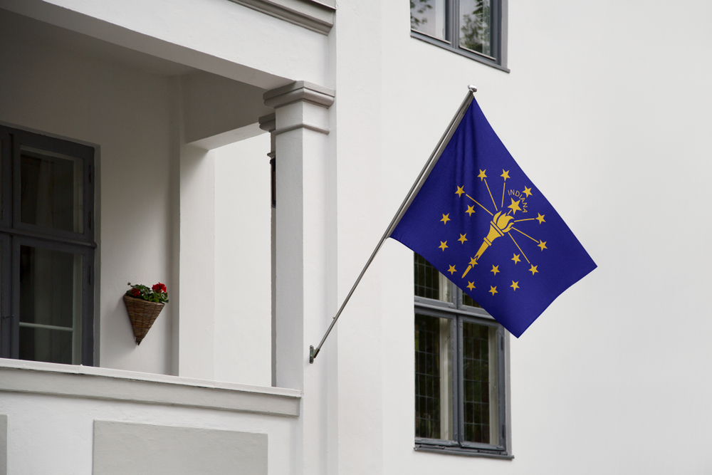 flag of Indiana state on a pole attached to a white building