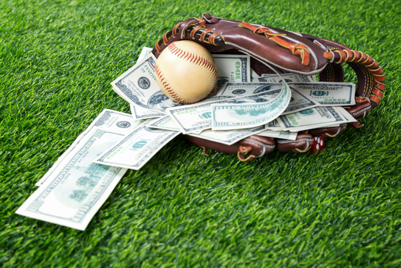 baseball in a glove with dollar bills