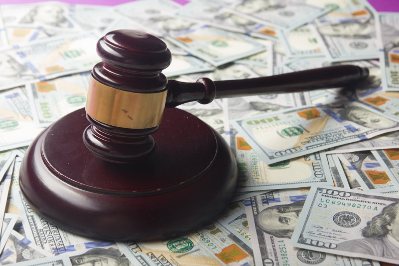 gavel on table covered in 100 dollar bills