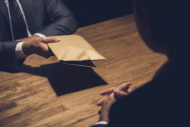 man giving bribe money in a brown envelope