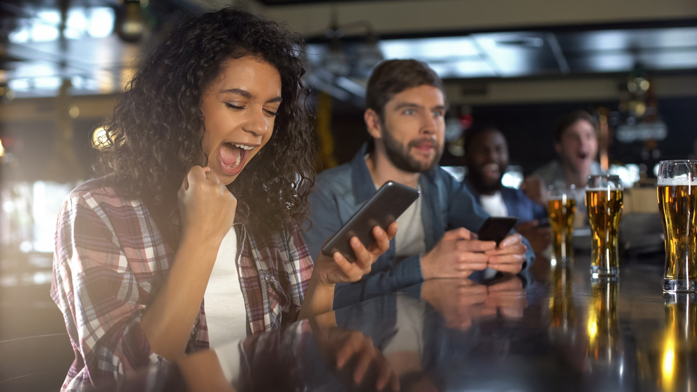 woman at the bar celebrating a mobile win