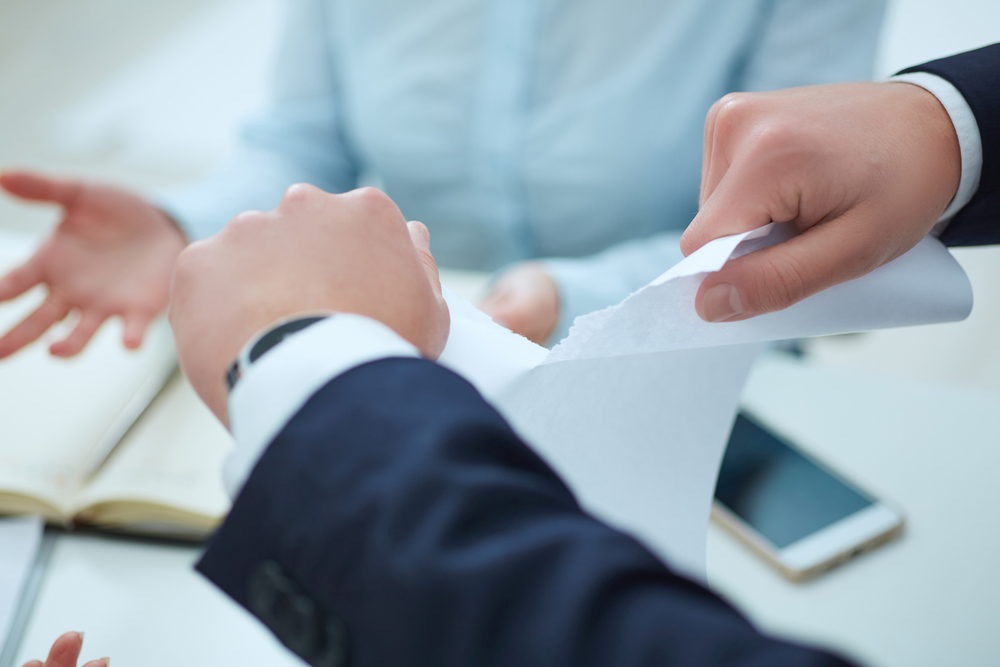 businessman tears up papers as colleague expresses surprise