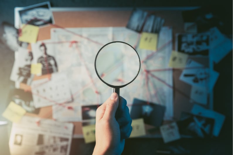 Magnifying glass looking at investigation board