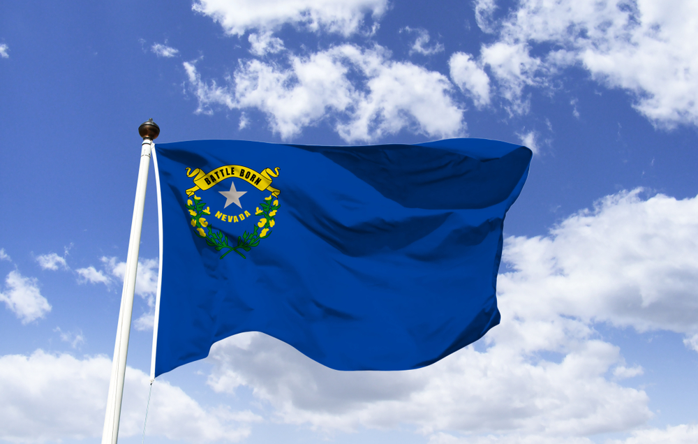 flag of Nevada state against blue sky and clouds background