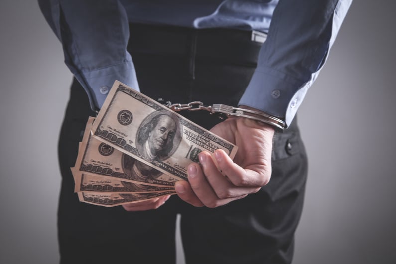 handcuffed man holding cash behind his back