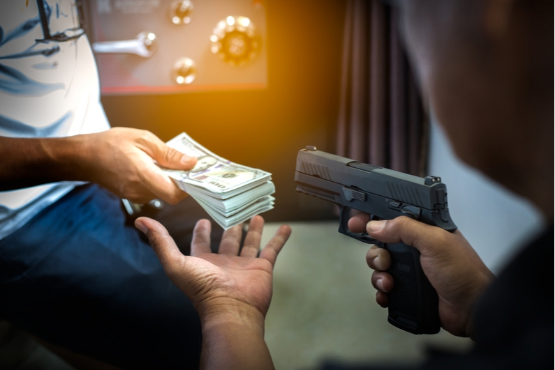 Man handing over cash to a gunman